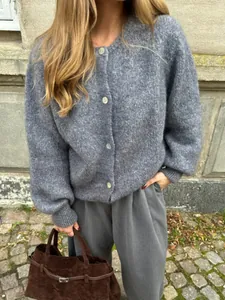 Detailansicht einer grauen, einreihigen Strickjacke, getragen von einem Modell im Freien