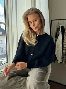 Detailansicht des weichen schwarzen Strick-Cardigans mit eleganten weißen Knöpfen und gemütlicher Textur
