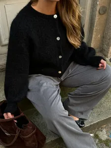 Detailansicht eines weichen schwarzen Strick-Cardigans mit einreihigen weißen Knöpfen.