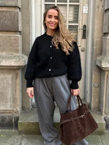Detailaufnahme der Textur einer flauschigen schwarzen Strickjacke mit Perlmuttknöpfen