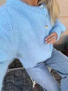 Nahaufnahme einer hellblauen flauschigen Strickjacke mit Perlmuttknöpfen