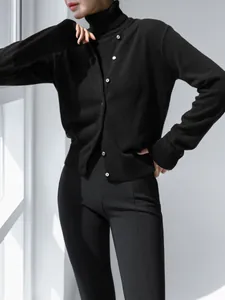 Detail view of black knitted two-piece set with turtleneck inner and button cardigan.