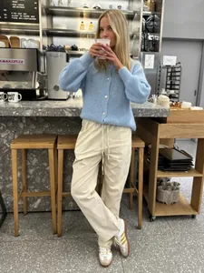 Detaillierte Aufnahme eines hellblauen Strick-Cardigans in einem gemütlichen Café-Ambiente.