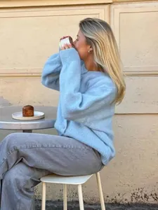 Nahaufnahme eines süßen, hellblauen Strick-Cardigans, getragen von einem Model im Café-Ambiente