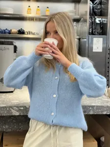 Detailaufnahme eines süßen hellblauen Strick-Cardigans mit Knöpfen im Café-Ambiente