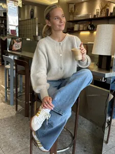 Nahaufnahme eines beigen Cardigans im Mohair-Stil mit Knöpfen im Café-Ambiente