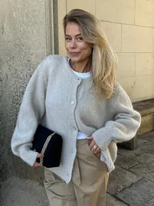 Gemütliche beige Strickjacke mit weißen Knöpfen, getragen von einem Model im Freien