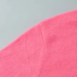 Nahaufnahme eines rosa Strick-Cardigans mit feiner Textur und Schulternaht-Detail