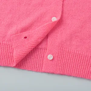 Detailaufnahme einer weichen rosa Strickjacke mit weißen Knöpfen und Rippsaum-Detail