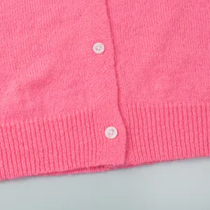 Detailansicht einer rosa Strickjacke mit weißen Knöpfen und geripptem Saum.