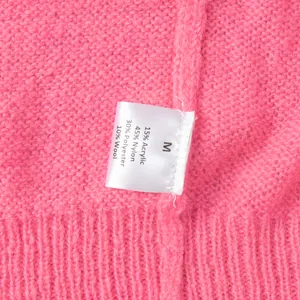 Detailaufnahme des Materialetiketts einer pinkfarbenen, bonbonfarbenen Strickjacke aus Strick