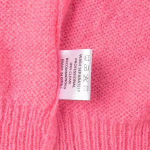 Detailansicht des Pflegeetiketts an einer rosa gestrickten Strickjacke in Bonbonfarben