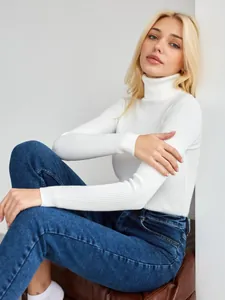 Detailansicht eines weißen Rollkragenpullovers aus Rippstrick, getragen mit Jeanshose