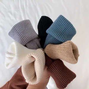 Bundle of colorful ribbed mock neck sweaters showing soft knit texture and variety.