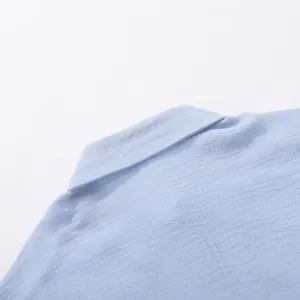 Dettaglio del colletto e del tessuto in cotone stropicciato su una camicia azzurra.
