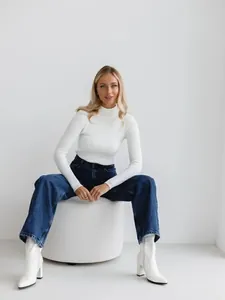 Elegant detail shot of white ribbed knit turtleneck sweater worn by sitting model