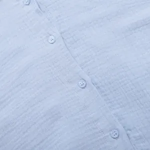 Vista macro che mostra la trama del tessuto in crêpe di cotone azzurro e i bottoni.