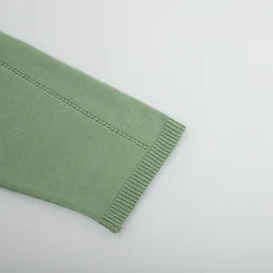 Close-up macro view of sage green ribbed knit sweater cuff with decorative stitching detail