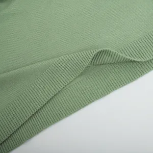 Detailed close-up of sage green ribbed knit texture on the hem of a winter sweater