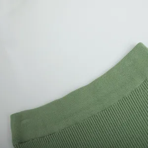 Detailed close-up view of the green knitted fabric texture and ribbed waistband detail