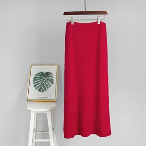 Full length view of a vibrant red knitted maxi skirt hanging on a minimalist backdrop