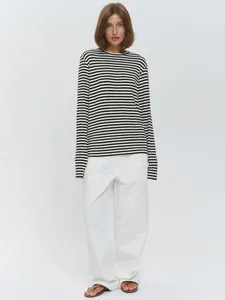 Volledige opname van een vrouw in een zwart-wit gestreept katoenen T-shirt met mouw.