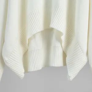 Close-up detail of white knitted sweater ribbed hem showing soft premium knit texture
