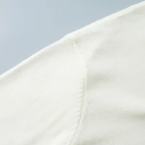 Macro detail of the high-quality white knit fabric and shoulder seam of a winter sweater.