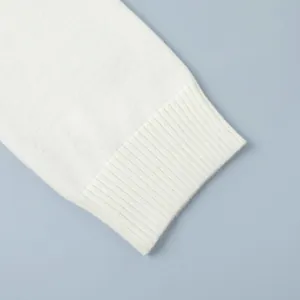 Detailed macro view showing the soft ribbed cuff of a premium white knit sweater