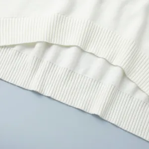 Close-up of ribbed hem texture on white knitted sweater two-piece set