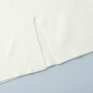 Detailed macro shot of the elegant side slit on a white ribbed knit sweater or skirt