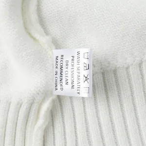 Detailed close-up of washing label on white knit sweater with care instructions.