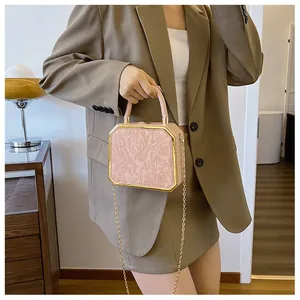 Detailed shot of a pink floral embossed box clutch bag with elegant gold chain and top handle
