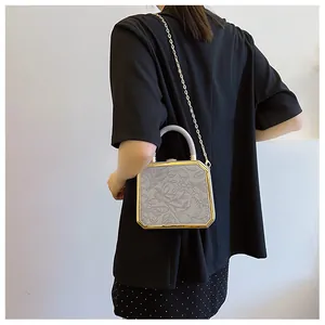 Close-up of a floral embossed grey evening box bag with a gold metal frame