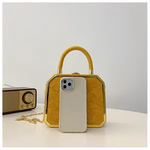 Yellow embossed dinner box bag shown next to a smartphone for size reference scale