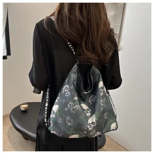 Achteraanzicht van model met grote nylon schoudertas met schedel en bloemenprint.