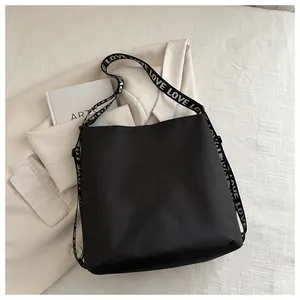 Detailweergave van een zwarte nylon crossbodytas met een brede schouderriem met LOVE-patroon