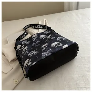 Detail van nylon crossbodytas met donker schedel- en bloemenpatroon en onderaanzicht.