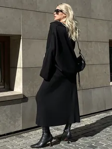 Full length street style view of black V-neck knit sweater and matching skirt set