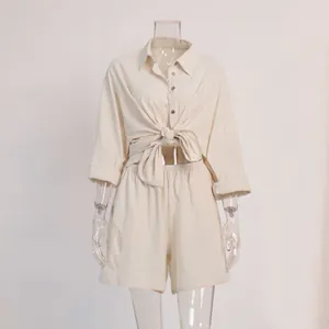 Detail of beige two-piece resort set showing the tied-waist shirt and shorts.