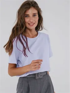 Detailaufnahme einer Frau im lavendelfarbenen Rundhals-T-Shirt mit grauer Hose