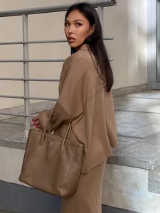 Stylish brown knit V-neck sweater and midi skirt set worn by a model in outdoor setting