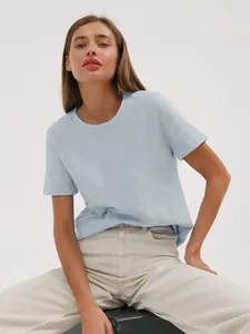 Ein Fashion-Model trägt ein hellblaues Baumwoll-T-Shirt mit Rundhalsausschnitt und beiger Hose.