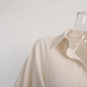 Close-up detail of the cream-colored linen-textured shirt collar and shoulder seams