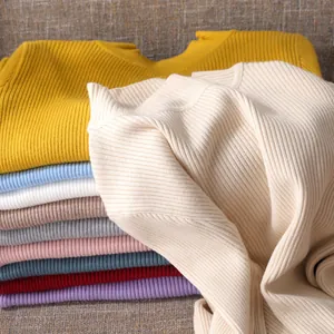 Detailansicht der weichen Rippstrickstruktur gestapelter Pullover in verschiedenen Farben