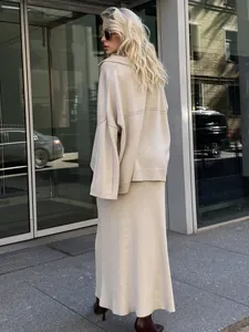 Back view of model in elegant beige knitted sweater and long skirt minimalist winter outfit