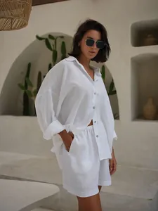 Detail of white oversized linen-style shirt and shorts set for summer vacations
