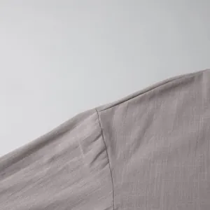 Close-up of the stitching and breathable cotton fabric texture on the grey cardigan sleeve.