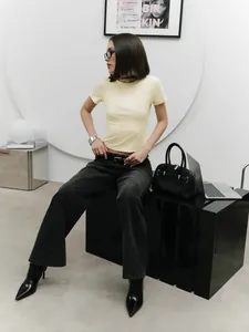 Model wearing a pale yellow short-sleeved fitted crop top with high-waisted black jeans