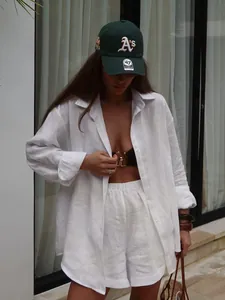 Lifestyle detail shot of white linen shirt and shorts set paired with green cap
